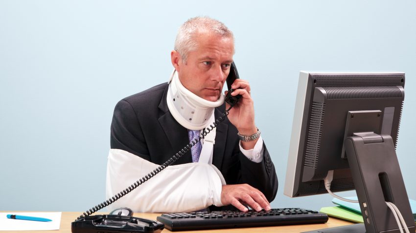 Injured businessman at his desk on the phone