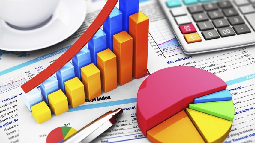 Business finance, tax, accounting, statistics and analytic research concept: macro view of office electronic calculator, bar graph charts, pie diagram and ballpoint pen on financial reports with colorful data with selective focus effect